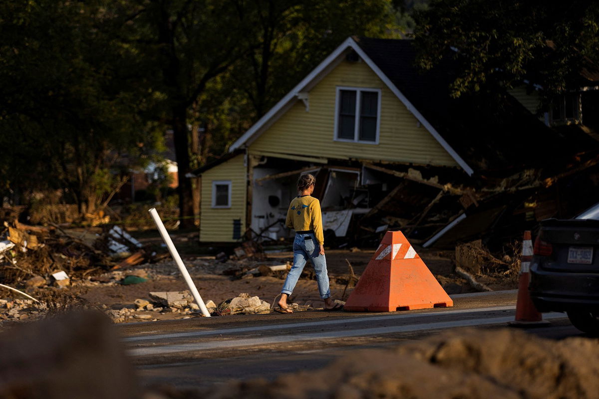 <i>Eduardo Munoz/Reuters via CNN Newsource</i><br/>A woman walks by a zone affected by floods following the passing of Hurricane Helene