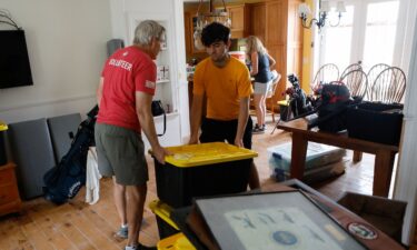 Rich Lorenzen and his son Sam Grande carry their belongings as they prepare to evacuate their home before the arrival of Hurricane Milton