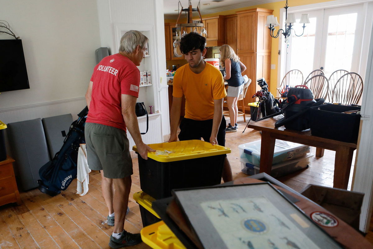 <i>Octavio Jones/Reuters via CNN Newsource</i><br/>Rich Lorenzen and his son Sam Grande carry their belongings as they prepare to evacuate their home before the arrival of Hurricane Milton