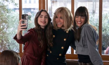 Brigitte Macron (center) appeared in an episode where she posed for a selfie with Lily Collins as Emily (left) and Thalia Besson as Genevieve (right).