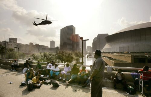 People seek high ground on Interstate 90 as a helicopter prepares to land at the Superdome in New Orleans in August 2005.