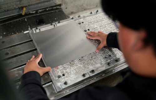 A worker places metal in a milling machine while producing parts for a Boeing 777 jetliner at Pathfinder Manufacturing