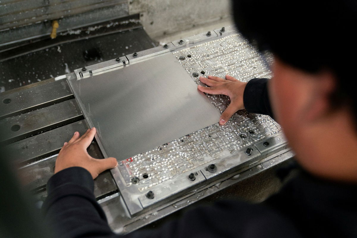 <i>David Ryder/Reuters via CNN Newsource</i><br/>A worker places metal in a milling machine while producing parts for a Boeing 777 jetliner at Pathfinder Manufacturing