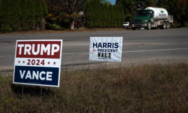 Signs showing support for both Kamala Harris and Donald Trump sit along a rural highway near Traverse City