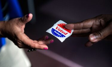 A poll worker hands out "I Voted Today" stickers.