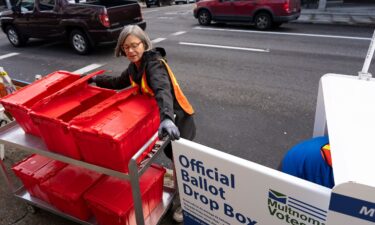 Election workers collect ballots from a newly placed ballot drop box outside the Multnomah County Elections Division office on Monday