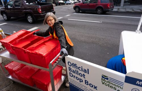 Election workers collect ballots from a newly placed ballot drop box outside the Multnomah County Elections Division office on Monday