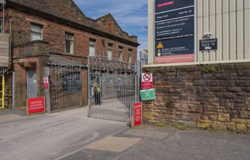 Pictured is an entrance gate to the BAE Systems Plc shipyard in Barrow-In-Furness