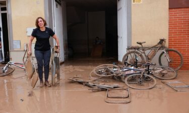 A woman carries chairs caked in mud after torrential rains caused flooding in La Alcudia