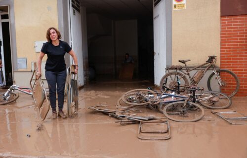 A woman carries chairs caked in mud after torrential rains caused flooding in La Alcudia