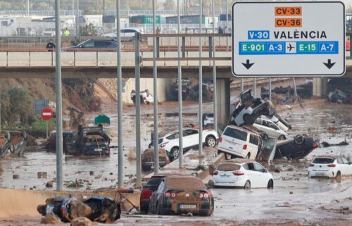 Damaged cars are seen along a road affected by torrential rains that caused flooding