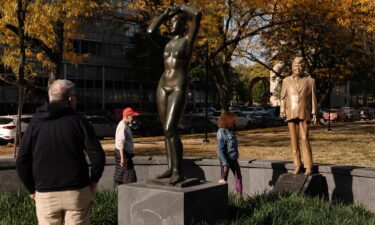 Pedestrians look at a statue of Donald Trump behind Gerhard Marcks' sculpture Maja