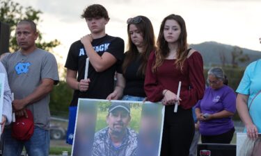 A photograph of Johnny Peterson is carried by his family during a candlelight vigil in Erwin