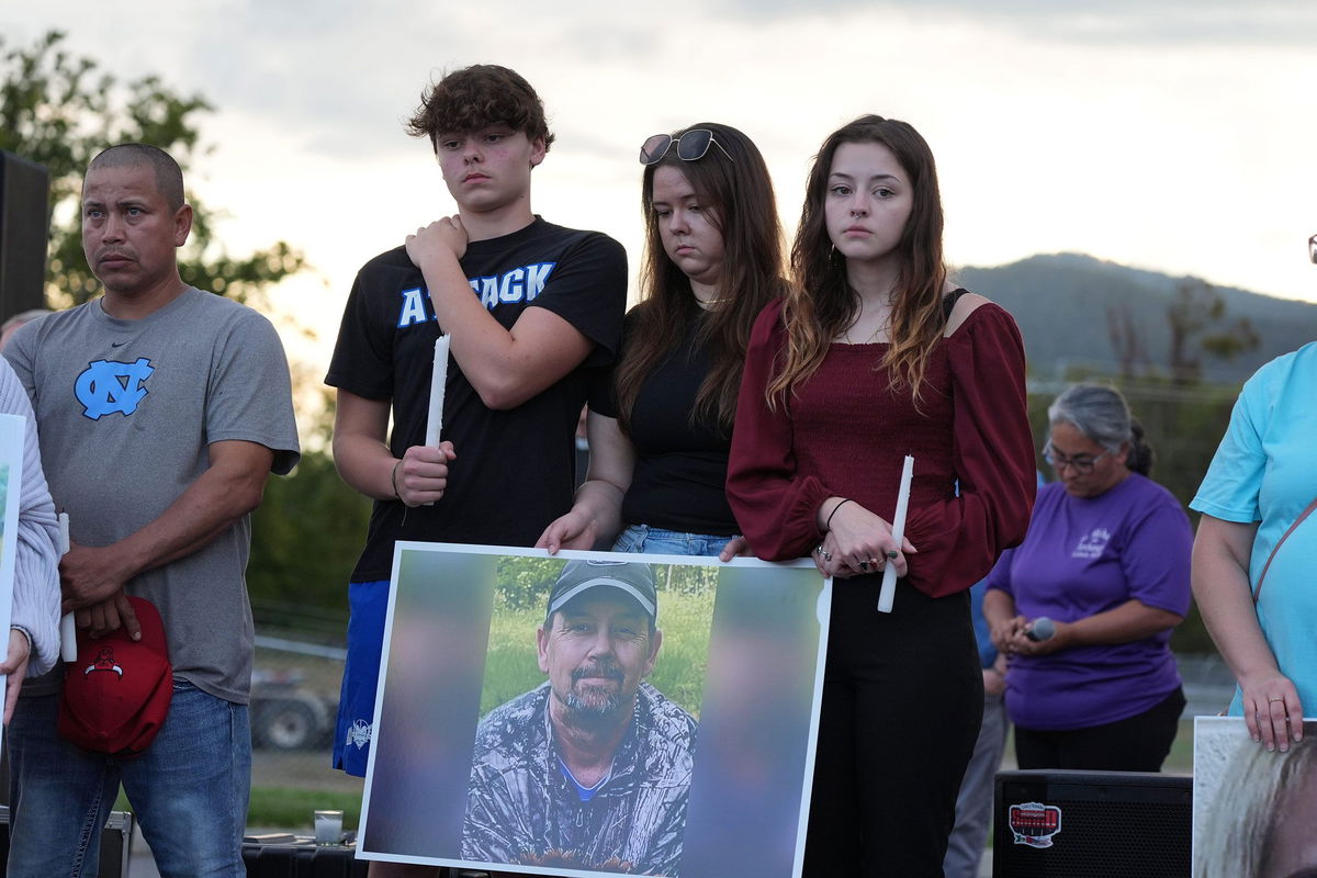 <i>Saul Young/News Sentinel/USA Today Network/Imagn Images via CNN Newsource</i><br/>A photograph of Johnny Peterson is carried by his family during a candlelight vigil in Erwin