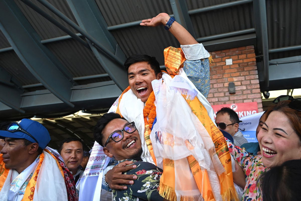 <i>Prakash Mathema/AFP/Getty Images via CNN Newsource</i><br/>Nepali mountaineer Nima Rinji Sherpa waves upon his arrival at the airport in Kathmandu on October 14.