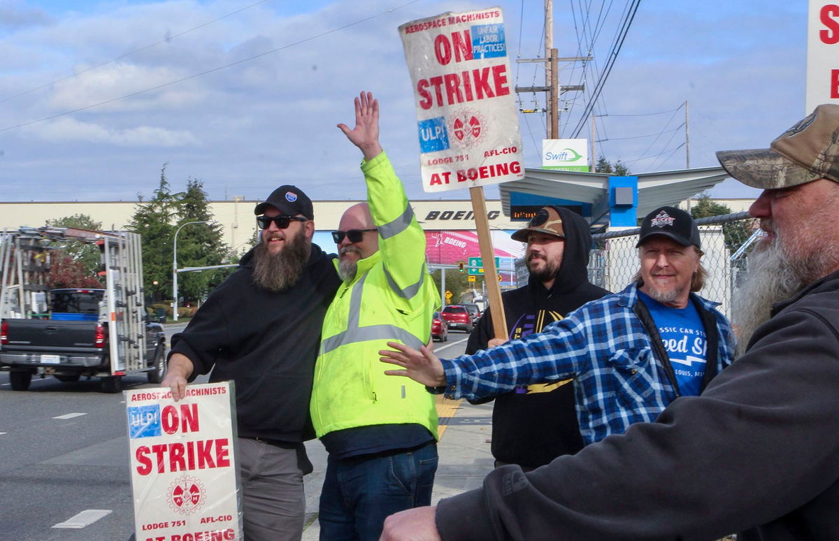 <i>Manuel Valdes/AP via CNN Newsource</i><br/>Union machinists wave signs next to the company's factory in Everett