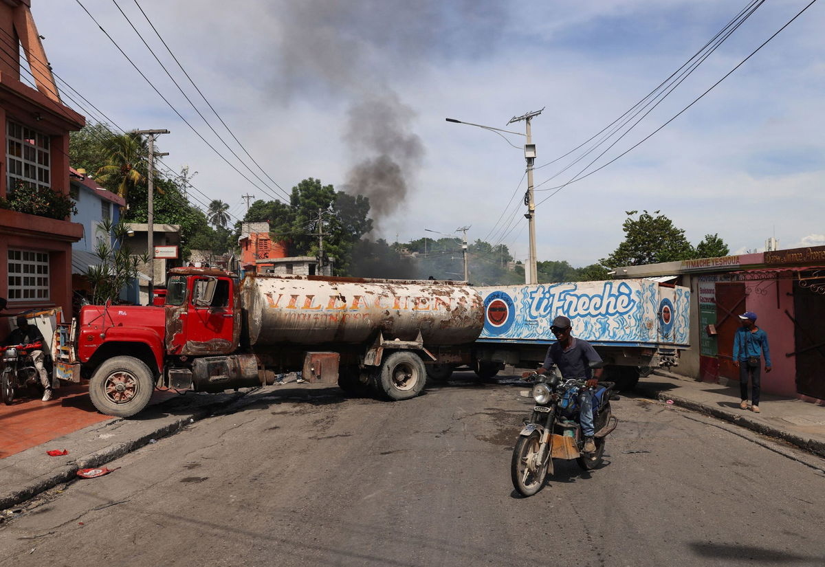 <i>Ralph Tedy Erol/Reuters via CNN Newsource</i><br/>A motorcyclist drives around trucks blocking the road as heavily-armed gangs