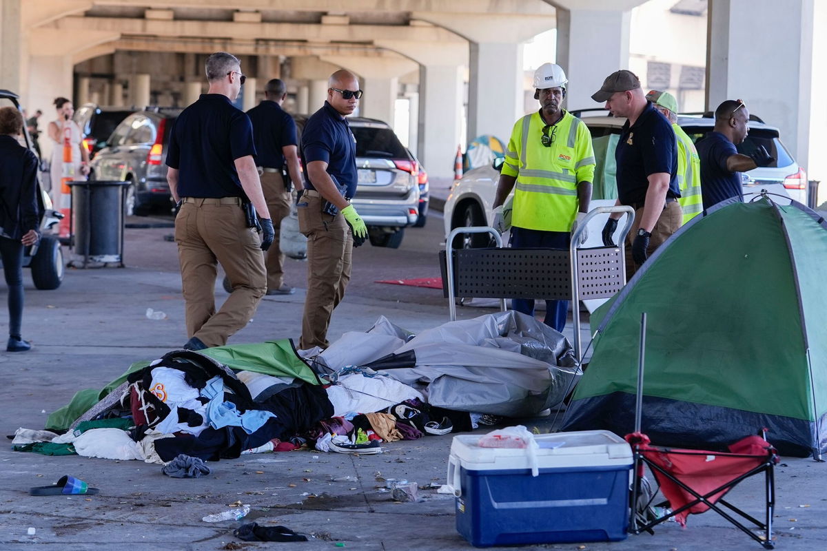 <i>Gerald Herbert/AP via CNN Newsource</i><br/>Louisiana State police give instructions to people living in a homeless encampment to move to a different pre-designated location as they perform a sweep in advance of a Taylor Swift concert in New Orleans