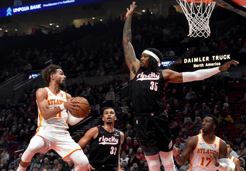 Atlanta Hawks guard Trae Young, left, looks to pass the ball against Portland Trail Blazers center Robert Williams III (35) as Trail Blazers forward Toumani Camara (33) defends during the first half of an NBA basketball game in Portland, Ore., Sunday, Nov. 17, 2024.