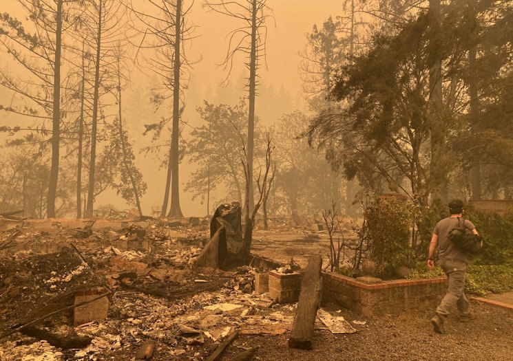 Sam Drevo walks by the burned foundation of his mother’s home in Gates following the 2020 Labor Day fires.