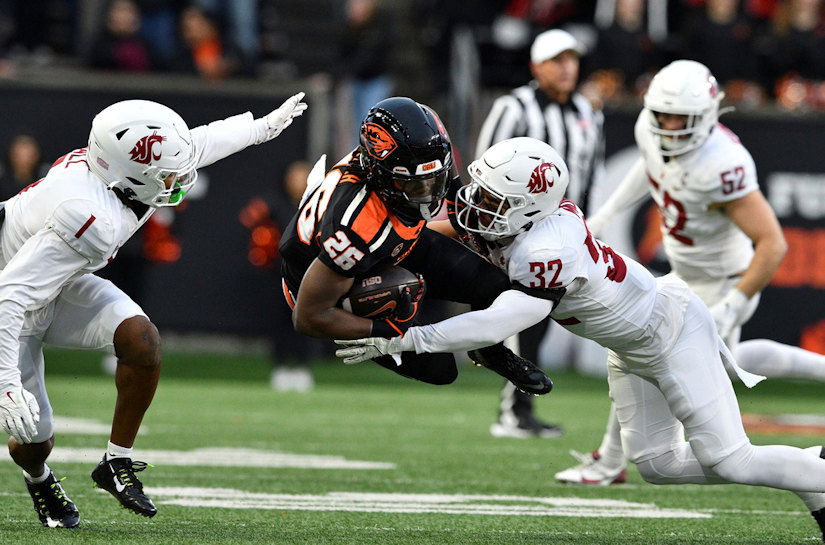 Washington State defensive backs Stephen Hall (1) and Tanner Moku (32) tackle Oregon State running back Salahadin Allah (26) during the first half of an NCAA college football game Saturday, Nov. 23, 2024, in Corvallis