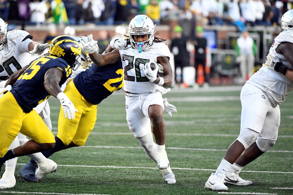 Oregon running back Jordan James (20) runs with the ball and is chased by Michigan linebacker Ernest Hausmann (15) and defensive lineman Rayshaun Benny (26) during the second half of Saturday's game in Ann Arbor, Mich. Oregon defeated Michigan 38-17.