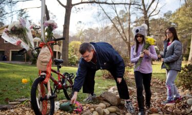 Jason Hoffman places flowers at a makeshift memorial outside the home of Elrey "Bud" and June Runion in January 2015 in Marietta