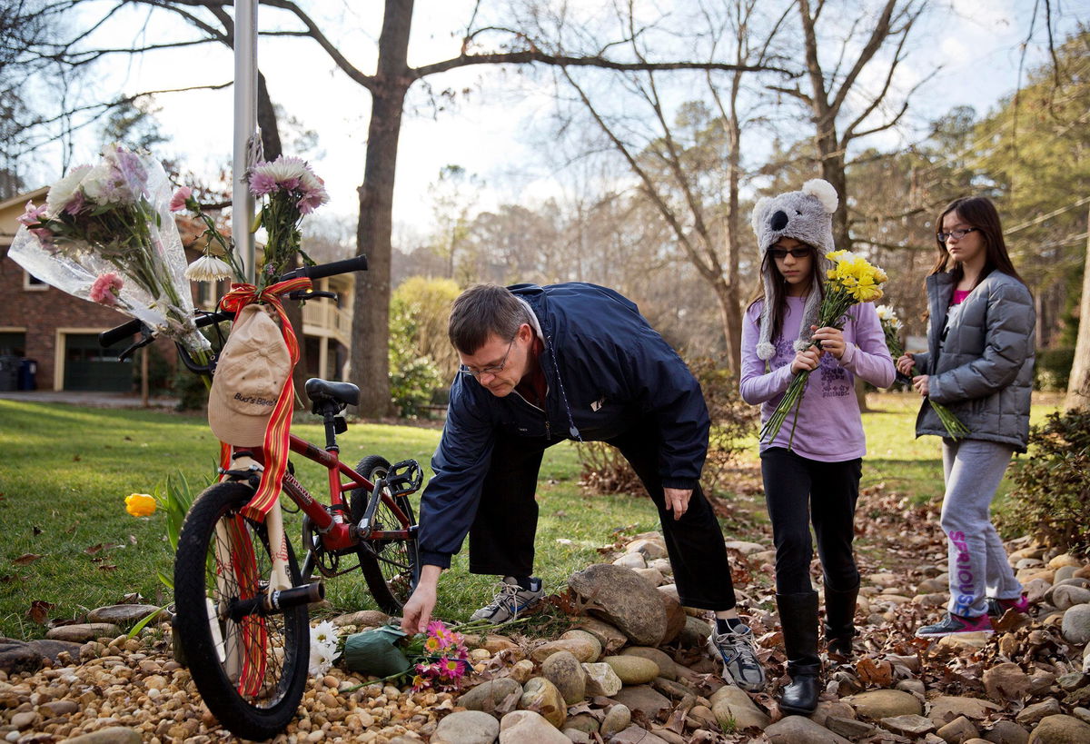 <i>David Goldman/AP via CNN Newsource</i><br/>Jason Hoffman places flowers at a makeshift memorial outside the home of Elrey 