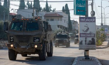 Israeli army vehicles drive down a road during a raid in Qabatiya