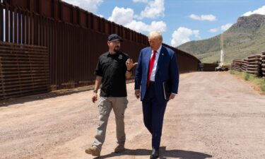 National Border Patrol Council board member Art Del Cueto walks with Trump along the US-Mexico border in August.