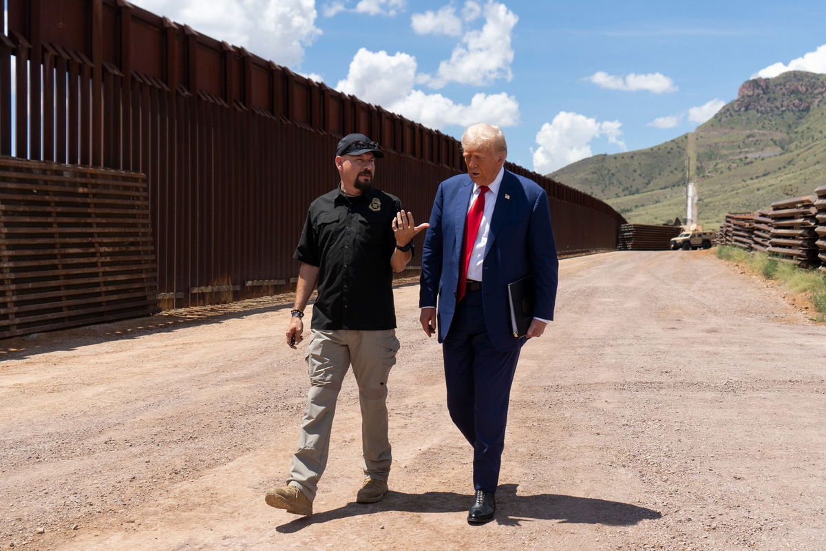 <i>Rebecca Noble/Getty Images via CNN Newsource</i><br/>National Border Patrol Council board member Art Del Cueto walks with Trump along the US-Mexico border in August.