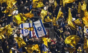 Maccabi supporters wave yellow flags next to Israeli flags during the UEFA Europa League football match between Ajax Amsterdam and Maccabi Tel Aviv at the Johan-Cruijff stadium