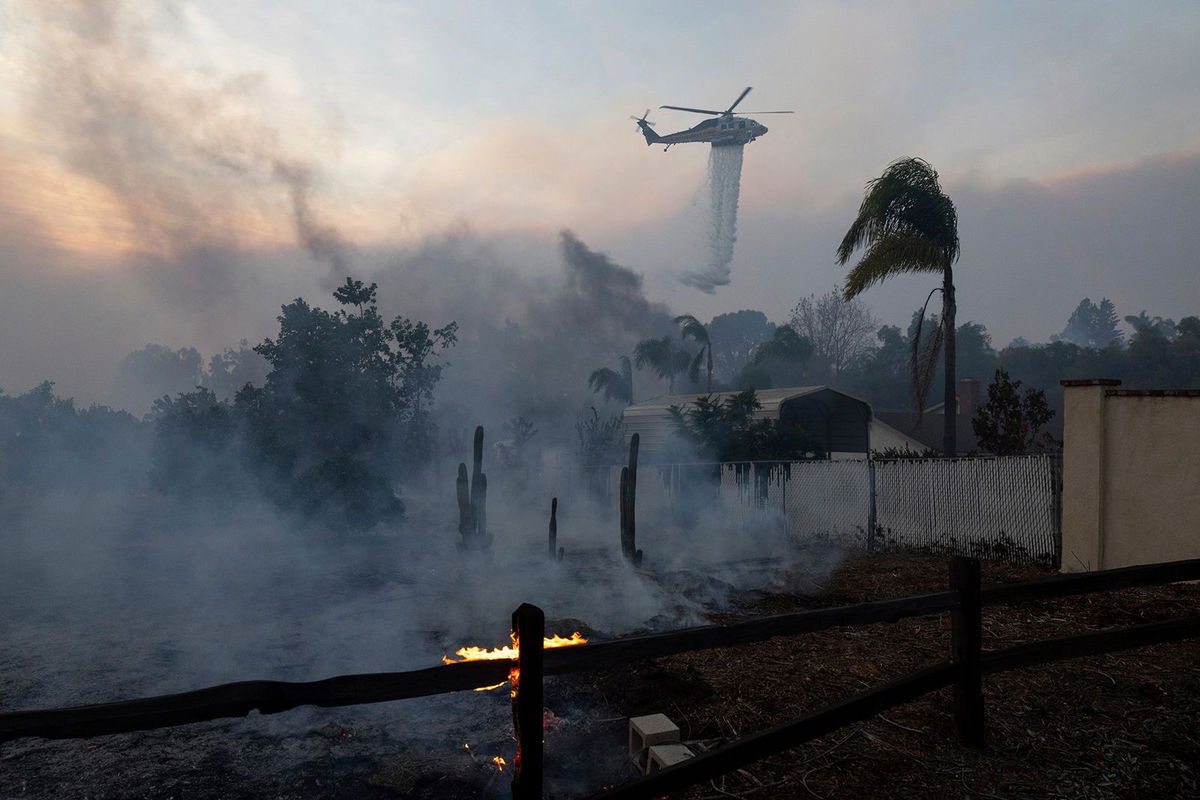 <i>Qian Weizhong/VCG/AP via CNN Newsource</i><br/>A helicopter drops water over a burning structure during a fast-moving wildfire in Moorpark