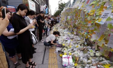 A woman places a flower for a South Korean woman who was stabbed to death at an exit of Gangham subway station in Seoul on May 21