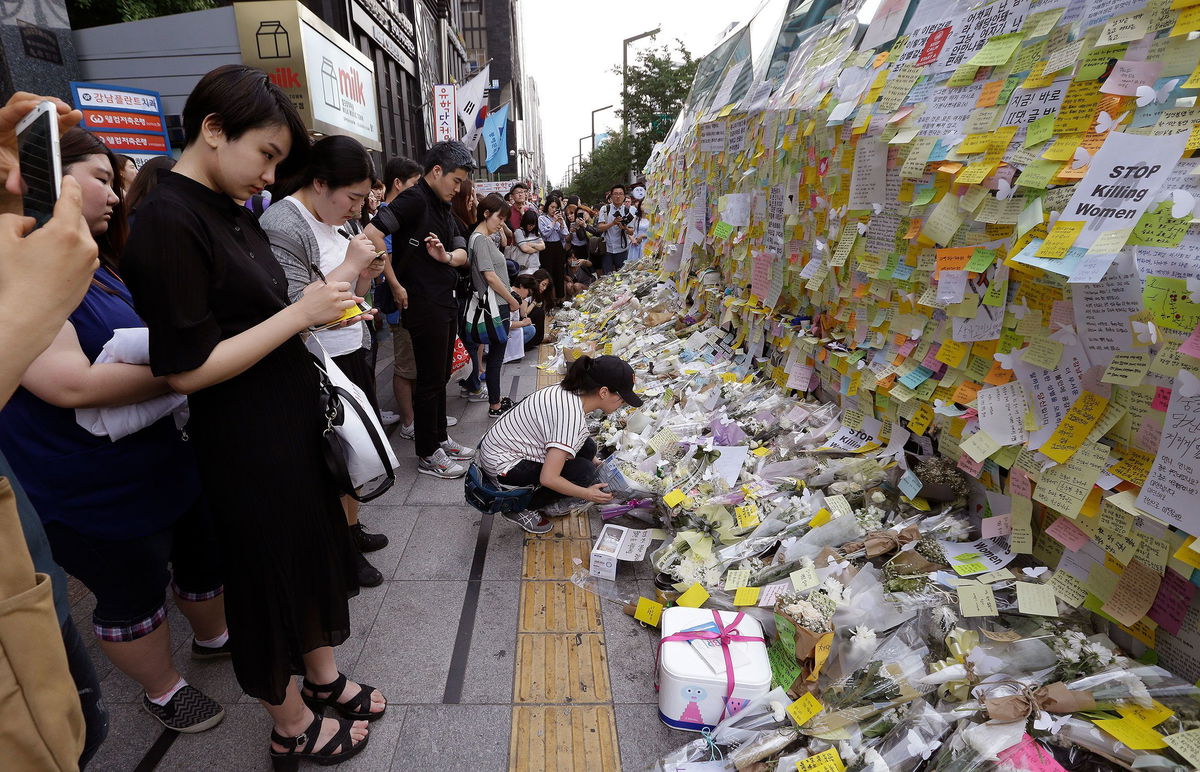 <i>Ahn Young-joon/AP via CNN Newsource</i><br/>A woman places a flower for a South Korean woman who was stabbed to death at an exit of Gangham subway station in Seoul on May 21