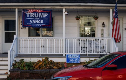 A Trump/Vance campaign flag hangs in front of one side of a duplex home while a Harris/Walz campaign sign is seen in front of the other side in Pen Argyl