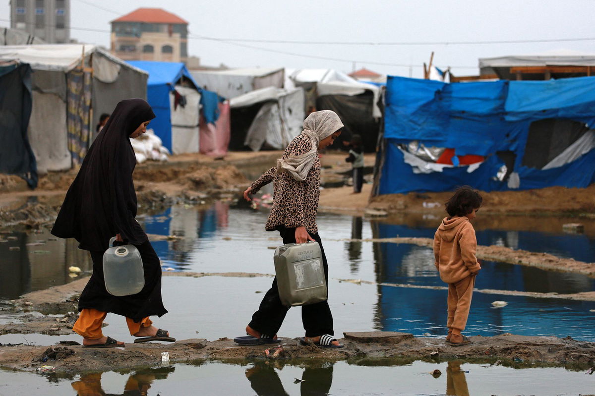 <i>Bashar Taleb/AFP/Getty Images via CNN Newsource</i><br/>Displaced Palestinian women carry water to their tent north of Deir el-Balah in Gaza on November 24.