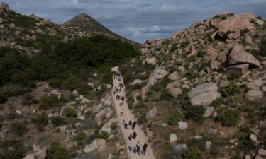 Asylum-seeking migrants from China and Turkey climb a hill while looking to surrender to immigration officials