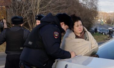 A Russian police officer questions a local resident at site of a drone attack in the village of Stanovoye