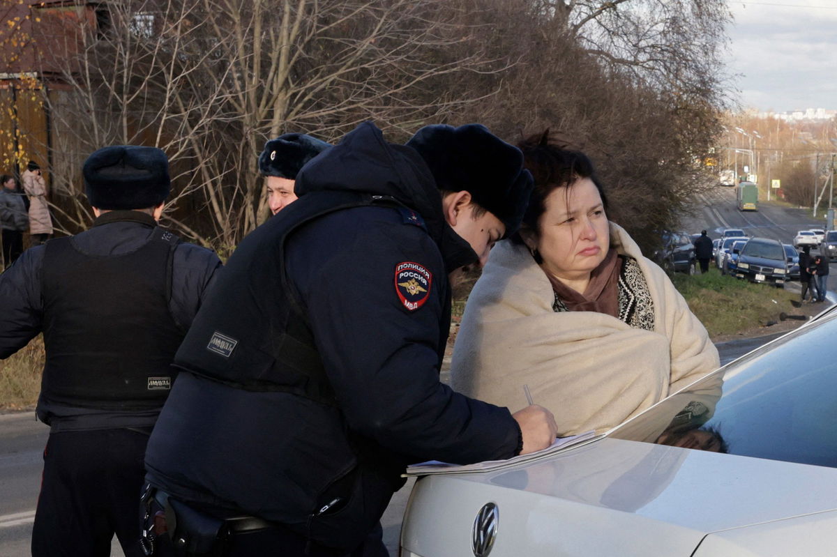 <i>Tatyana Makeyeva/AFP/Getty Images via CNN Newsource</i><br/>A Russian police officer questions a local resident at site of a drone attack in the village of Stanovoye