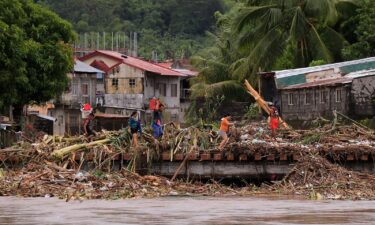 Residents cross a bridge filled with debris due to heavy rains brought about by Tropical Storm Trami in Polangui town