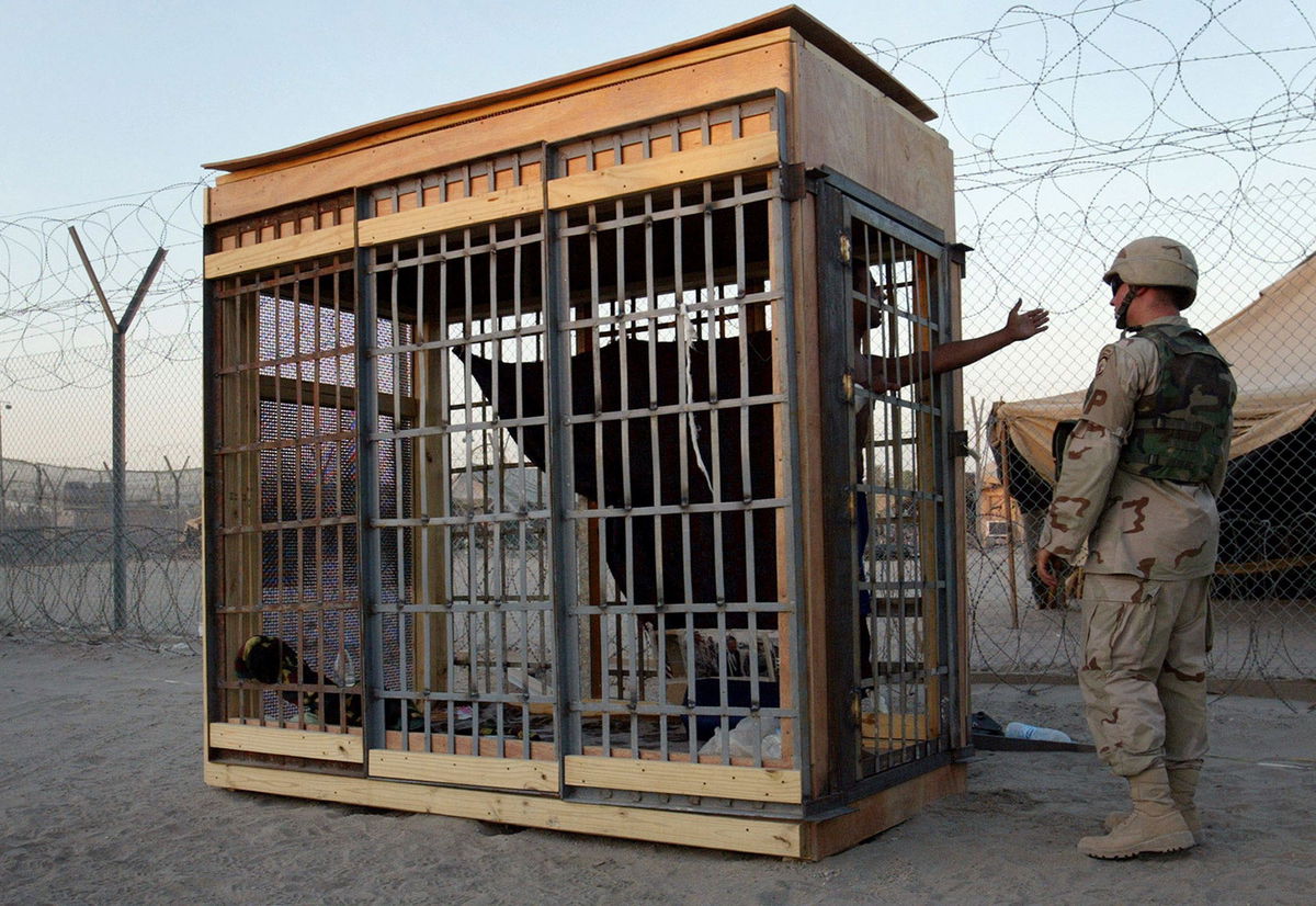 <i>John Moore/AP/File via CNN Newsource</i><br/>A detainee in an outdoor solitary confinement cell talks with a military police officer at the Abu Ghraib Prison in June 2004.