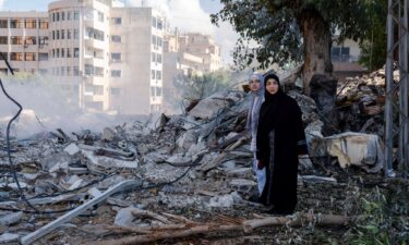 Two women stand next to destruction in the city center of Tyre