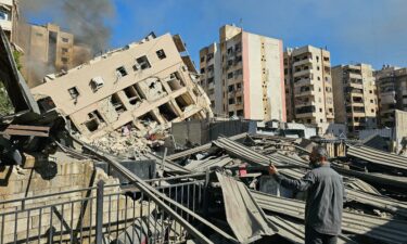 A man watches smoke rising behind a destroyed building following an Israeli airstrike on the district of Haret Hreik in Beirut's southern suburbs on November 16