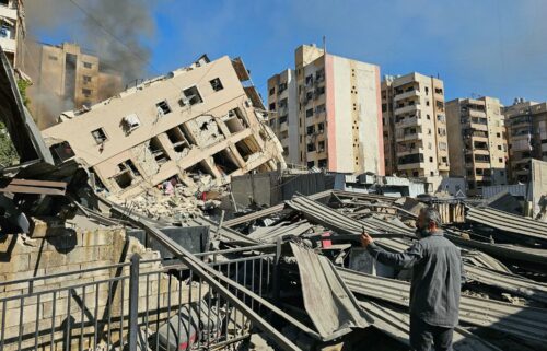 A man watches smoke rising behind a destroyed building following an Israeli airstrike on the district of Haret Hreik in Beirut's southern suburbs on November 16