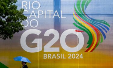 A woman walks carrying an umbrella during the G20 Social Summit in Rio de Janeiro