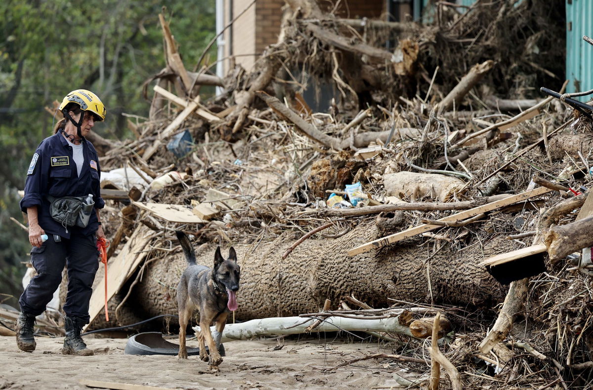 <i>Mario Tama/Getty Images North America/Getty Images via CNN Newsource</i><br/>A member of the FEMA Urban Search and Rescue Task Force searches a flood-damaged property with a search canine in the aftermath of Hurricane Helene along the Swannanoa River on October 4 in Asheville