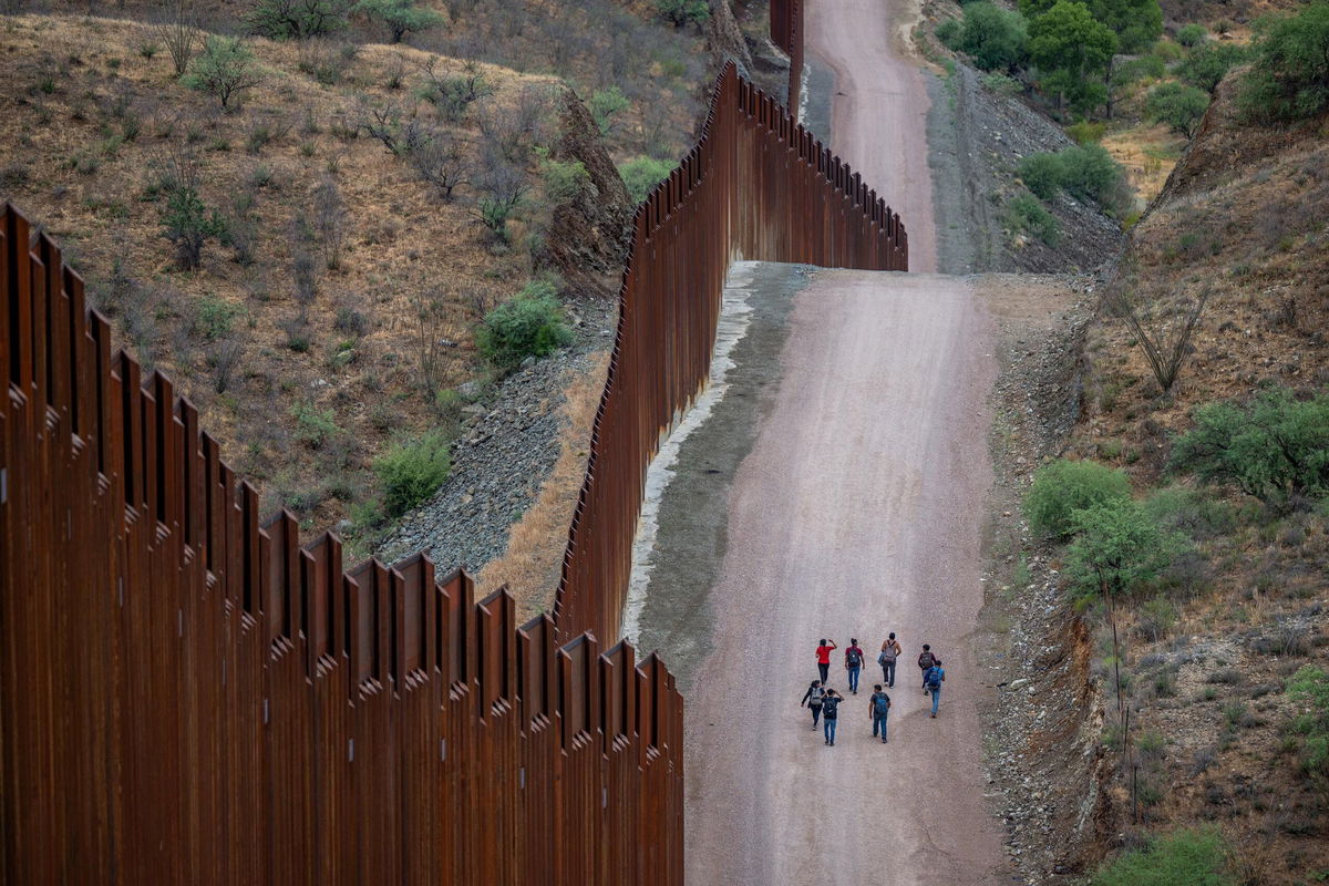 <i>Brandon Bell/Getty Images via CNN Newsource</i><br/>Migrants seeking asylum from Central and South America walk alongside border fencing in Ruby