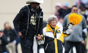 Colorado Buffaloes head coach Deion Sanders holds Peggy Coppom's hand before the Buffs' spring game at Folsom Field.