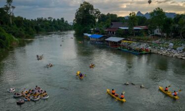 Foreign tourists kayaking and tubing on the Song River in Vang Vieng